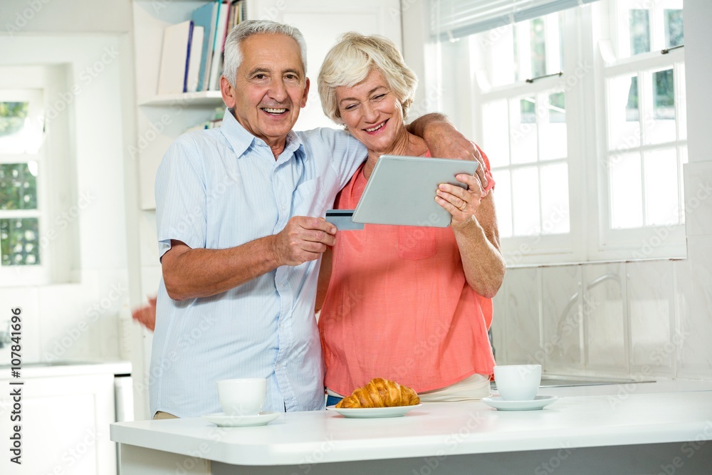 Happy senior couple with credit card while using digital tablet Happy senior couple with credit card while using digital tablet