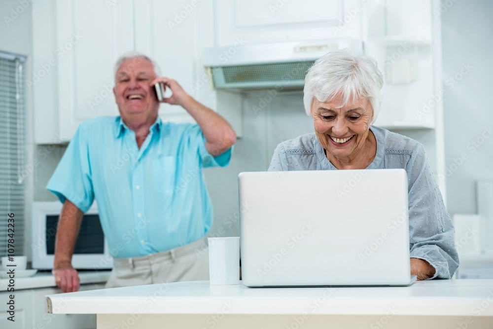 Happy senior man holding paper while talking on phone