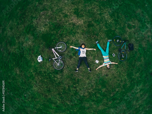 Young couple lying on the grass and biking, top view, a general