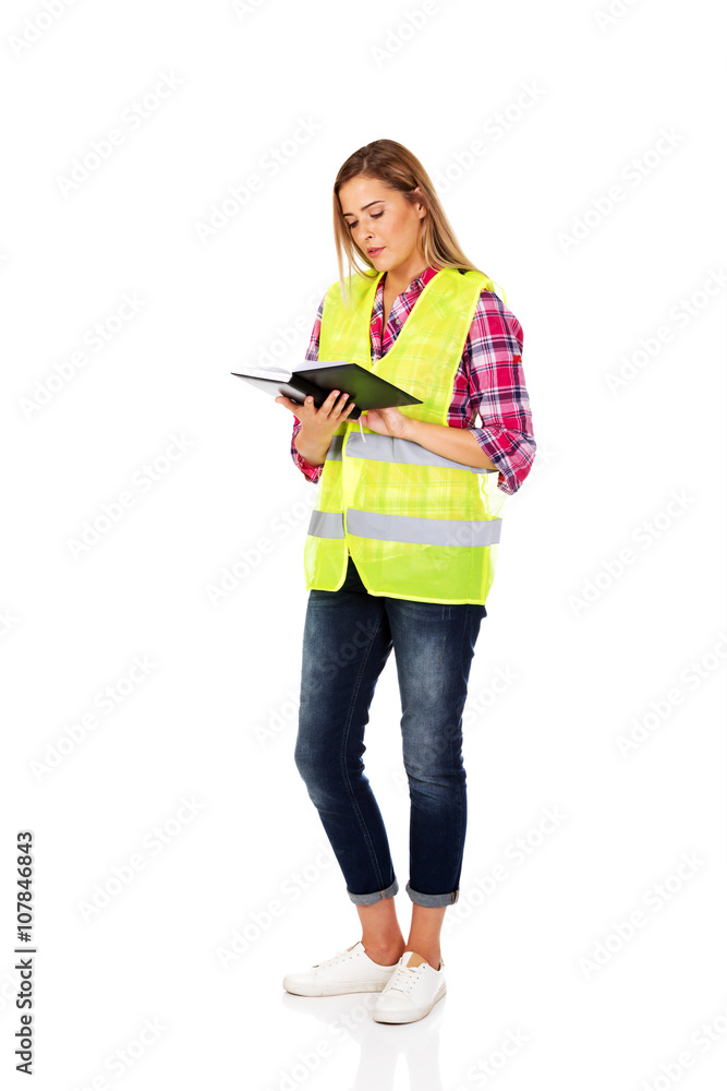 Female builder in a helmet and a vest with a notebook Female builder in a helmet and a vest with a notebook