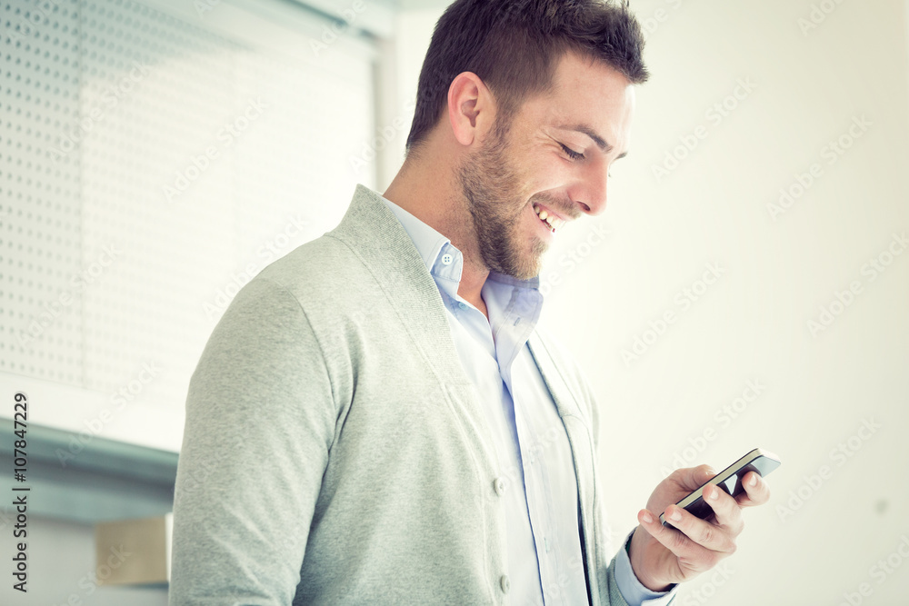 smiling young casual businessman talking on the phone at office smiling young casual businessman talking on the phone at office