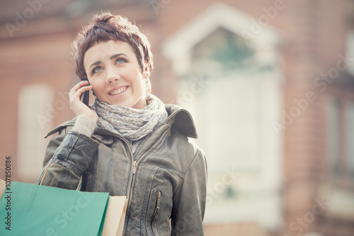 short hair smiling woman shop with phone in cityscape