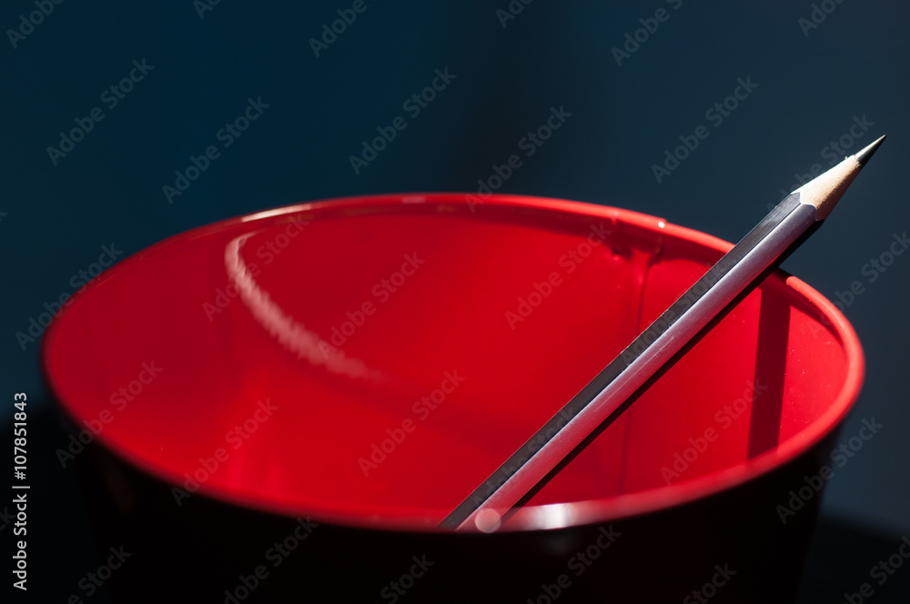 close up Pencil in a red bucket on dark blue wall background close up Pencil in a red bucket on dark blue wall background