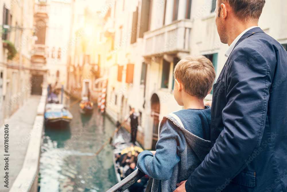 Father and son look together on venecian gondolas Father and son look together on venecian gondolas