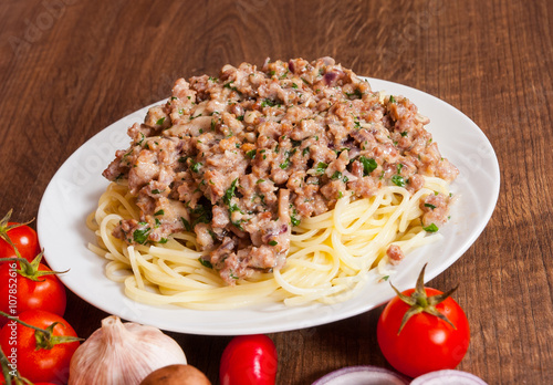 spaghetti with mushroom and minced meat in a plate on wooden table