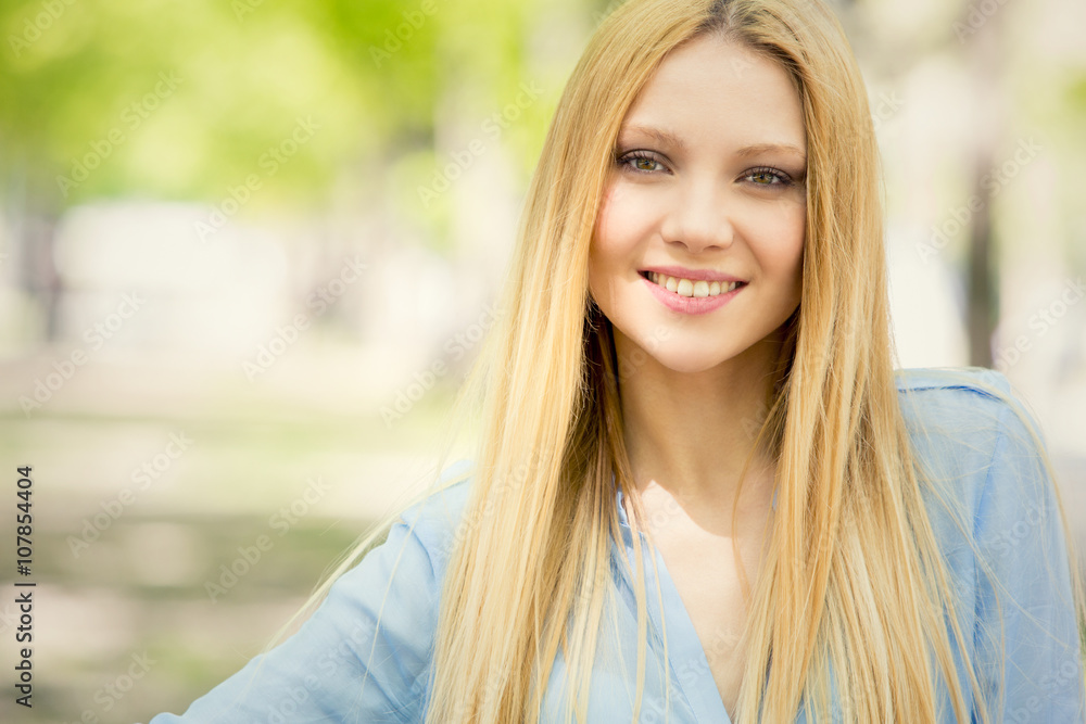 smiling blonde young woman portrait in a green cityscape smiling blonde young woman portrait in a green cityscape