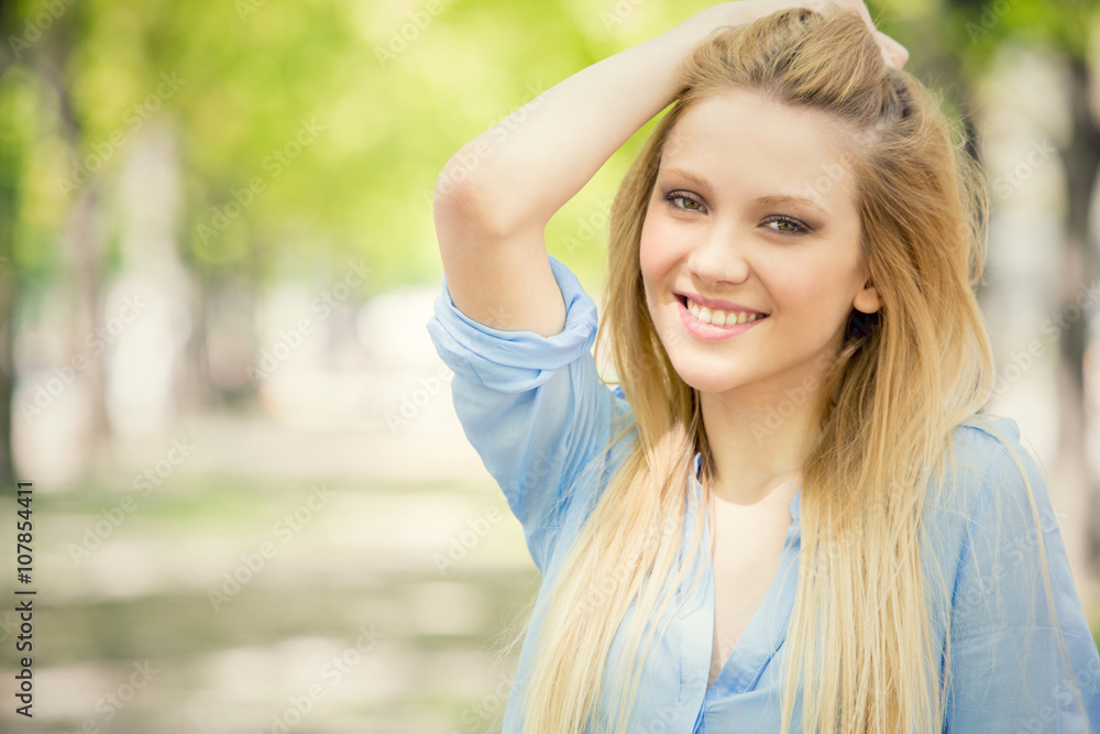 smiling blonde young woman portrait in a green cityscape smiling blonde young woman portrait in a green cityscape
