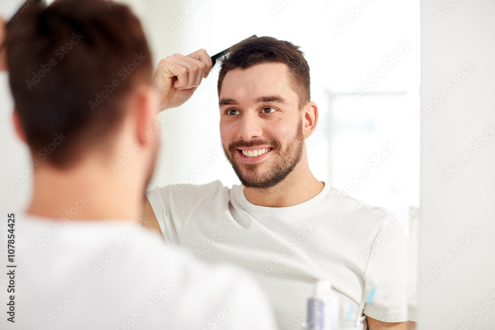 happy man brushing hair with comb at bathroom happy man brushing hair with comb at bathroom