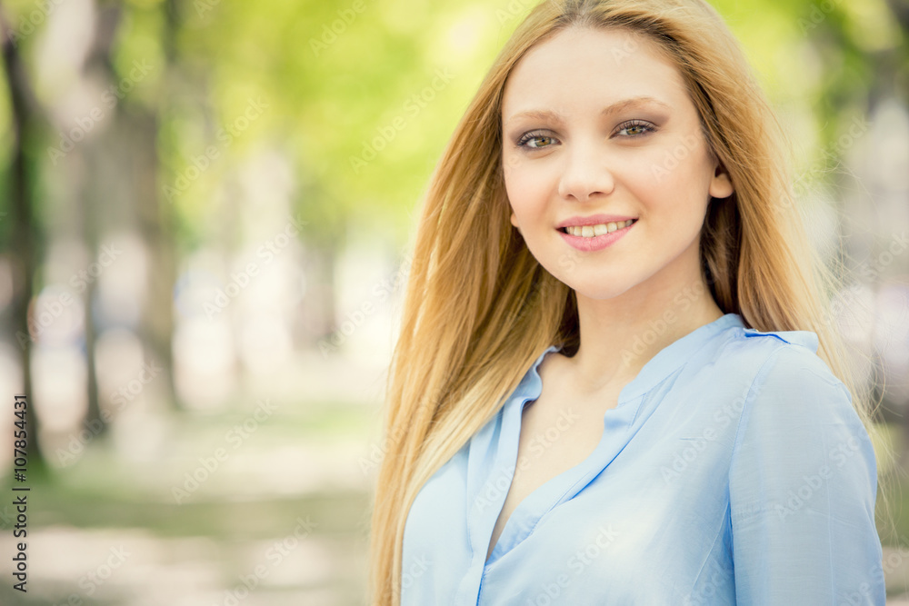 smiling blonde young woman portrait in a green cityscape smiling blonde young woman portrait in a green cityscape