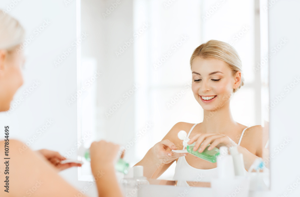 young woman with lotion washing face at bathroom young woman with lotion washing face at bathroom