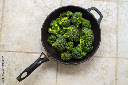 Broccoli in a dark black pan isolated on a stone tile