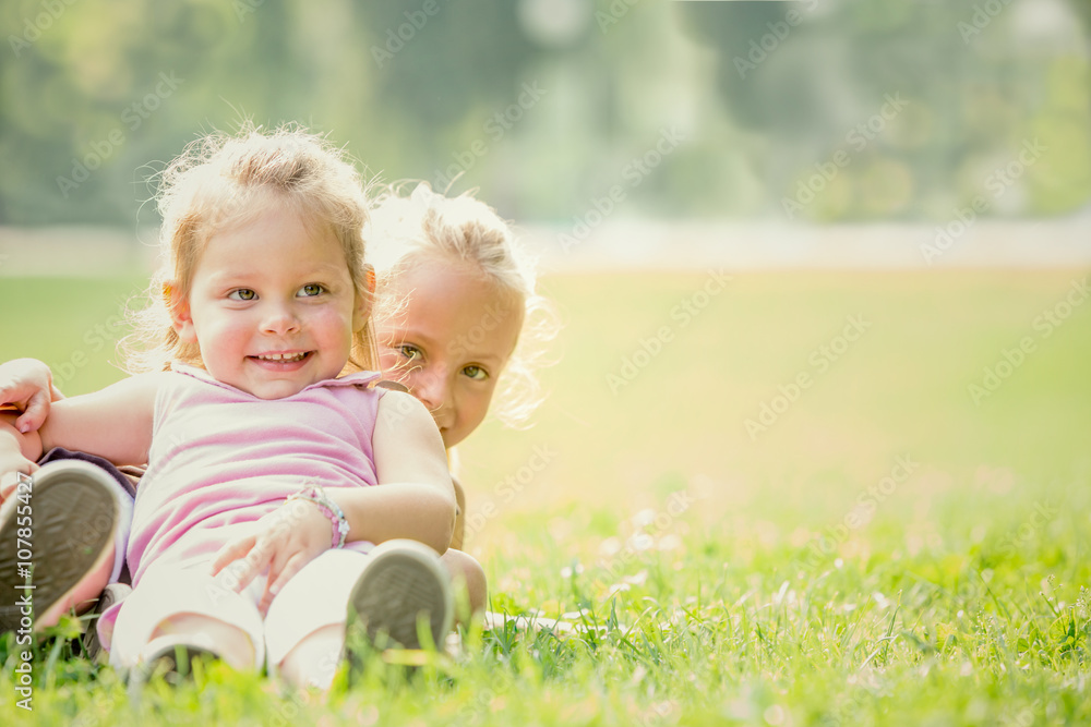 blonde smiling sister play in a garden blonde smiling sister play in a garden