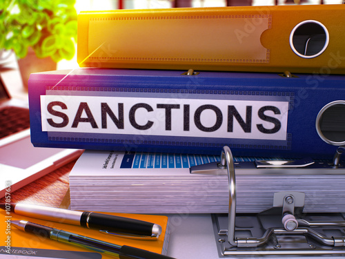 Sanctions - Blue Office Folder on Background of Working Table with Stationery and Laptop. Sanctions Business Concept on Blurred Background. Sanctions Toned Image. 3D. photo