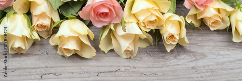Pink and yellow roses over wooden background
