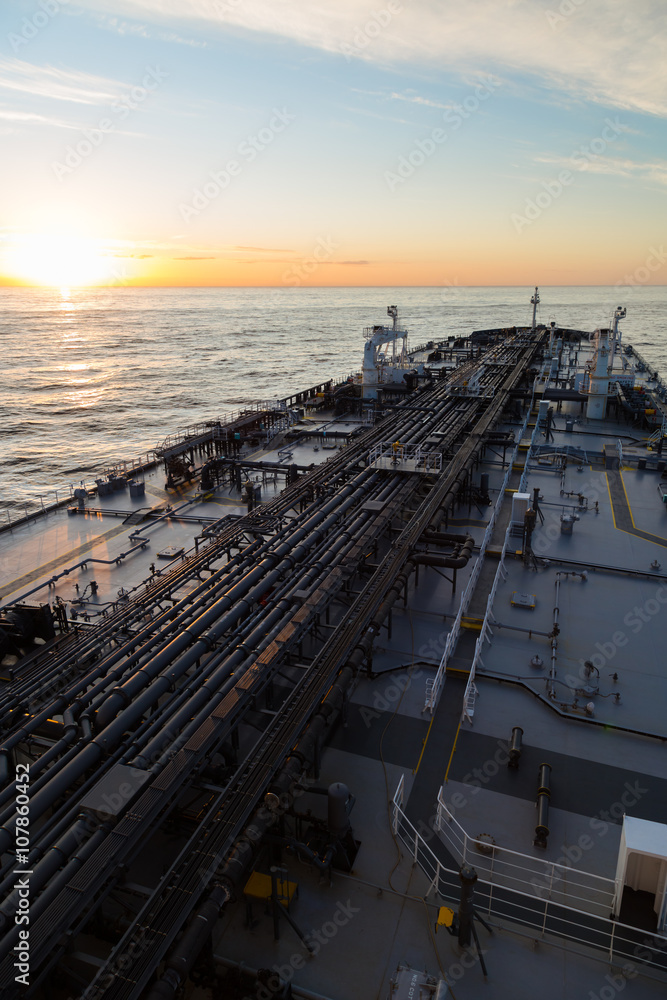 Vertical image oil tanker in ocean when sunset.
