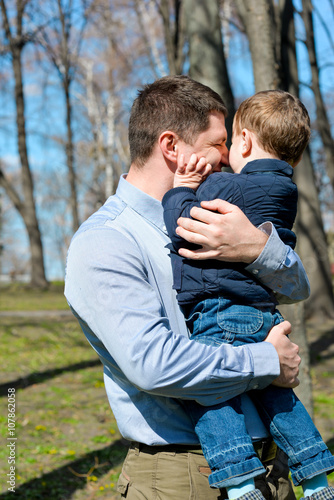 Father and son having fun outdoors on a spring sunny day. Happy smiling little boy in the arms of his dad. Concept of happy family life, love and happiness.  © ISOstudio