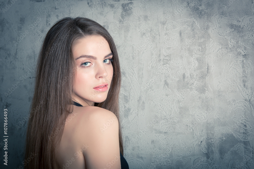 Fototapeta premium beautiful girl posing in a black evening dress. toned portrait in the studio