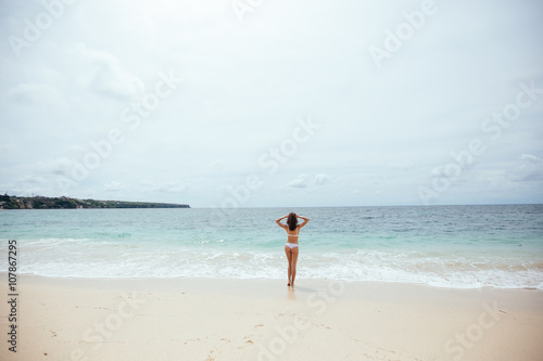 Beautiful girl in swimsuit walking along the beach.back view