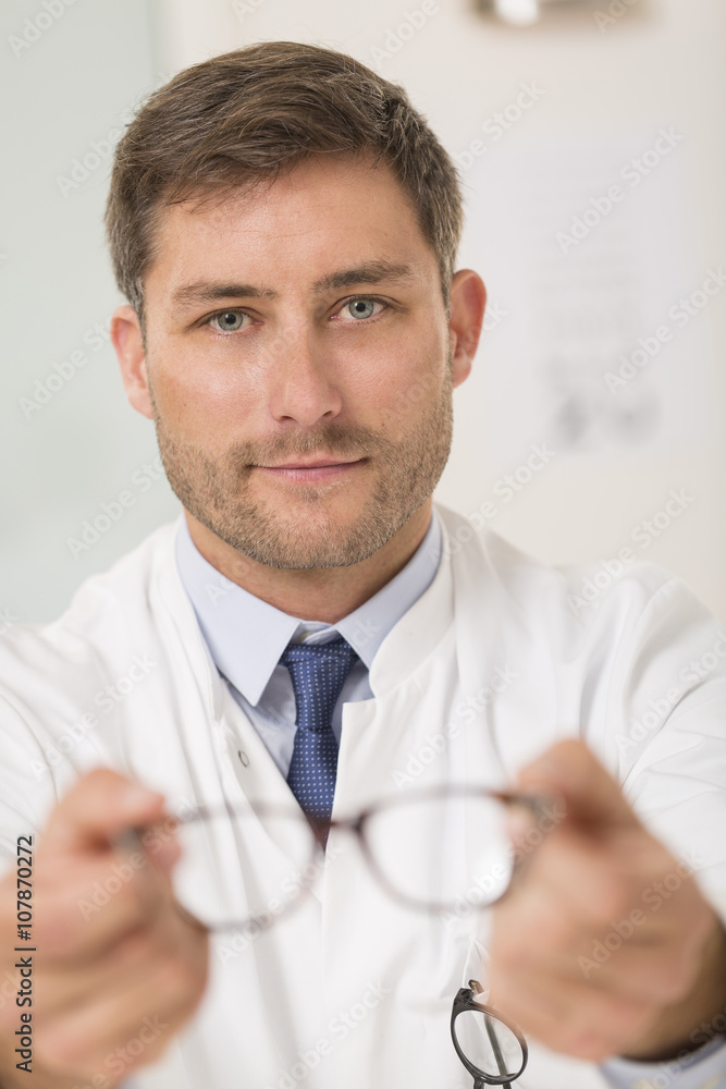 Optician giving new glasses to the patient