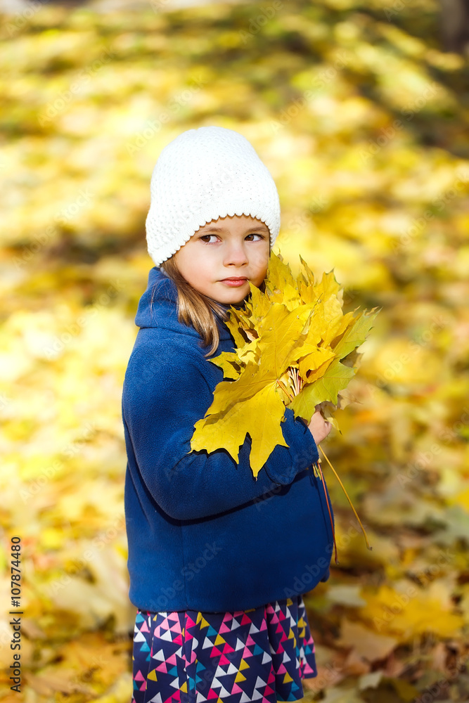 little girl keeps leafs in hand in park in the autumn