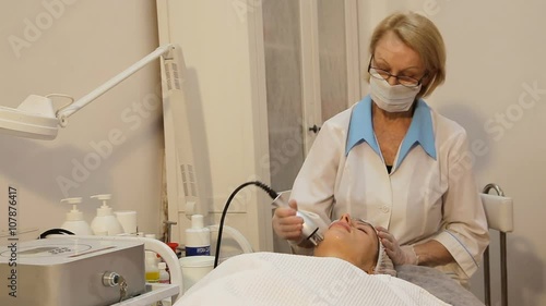 Head of young woman receiving electric ultrusound facial massage at beauty salon.Woman with closed eyes getting rf-lifting in a beauty salon.Woman having a stimulating facial treatment from a photo