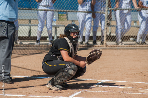 Strong softball player in black uniform waiting for the sign from the coach. 