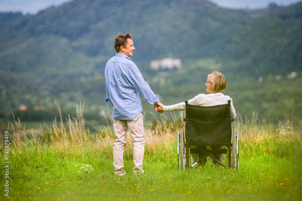 Senior man with woman in wheelchair, green autumn nature Senior man with woman in wheelchair, green autumn nature