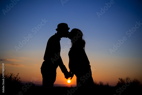 silhouette of a couple at sunset, kiss, maternity