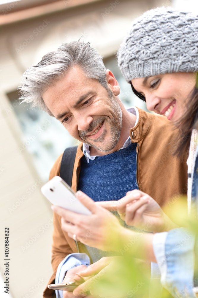 Trendy mature couple in town using smartphone Trendy mature couple in town using smartphone