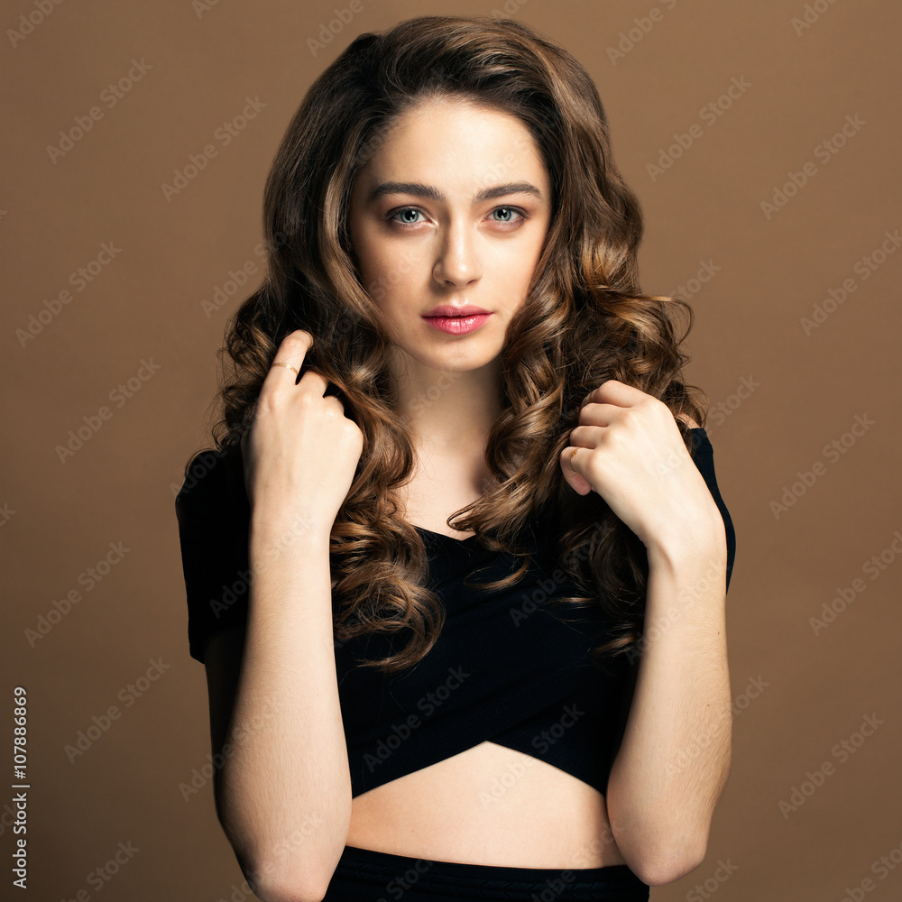 Fototapeta premium Fashion portrait of young woman with magnificent curly hair. Bru