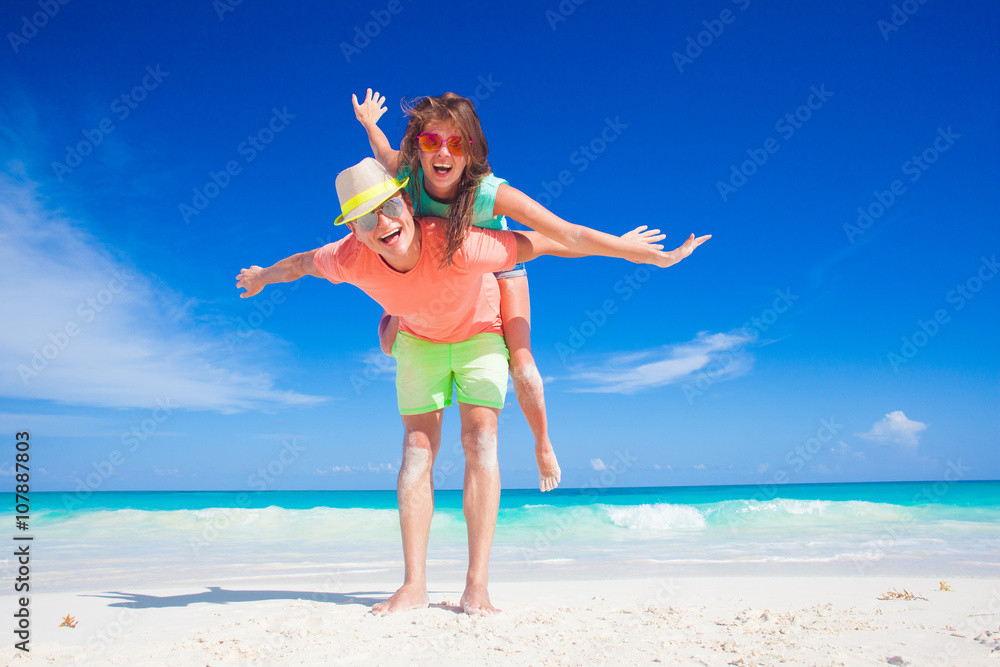 back view of couple in bright clothes having fun at tropical beach