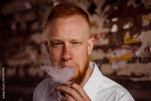 portrait of smoking young red hair man with beard photo