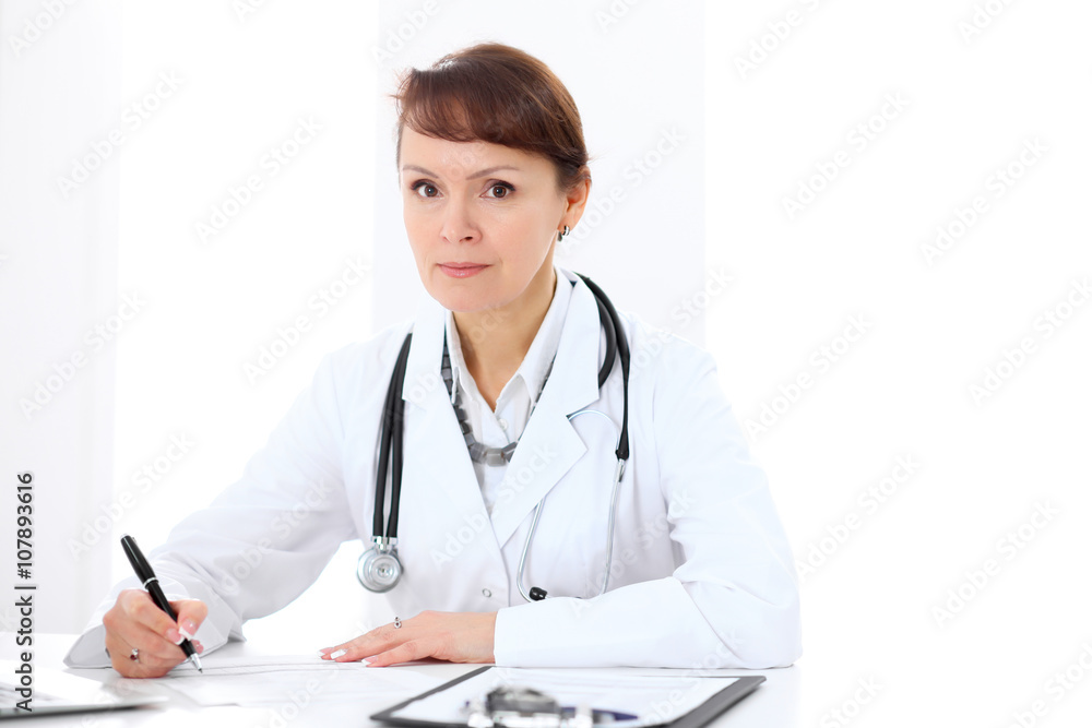 Woman doctor filling up medical history at the desk Woman doctor filling up medical history at the desk
