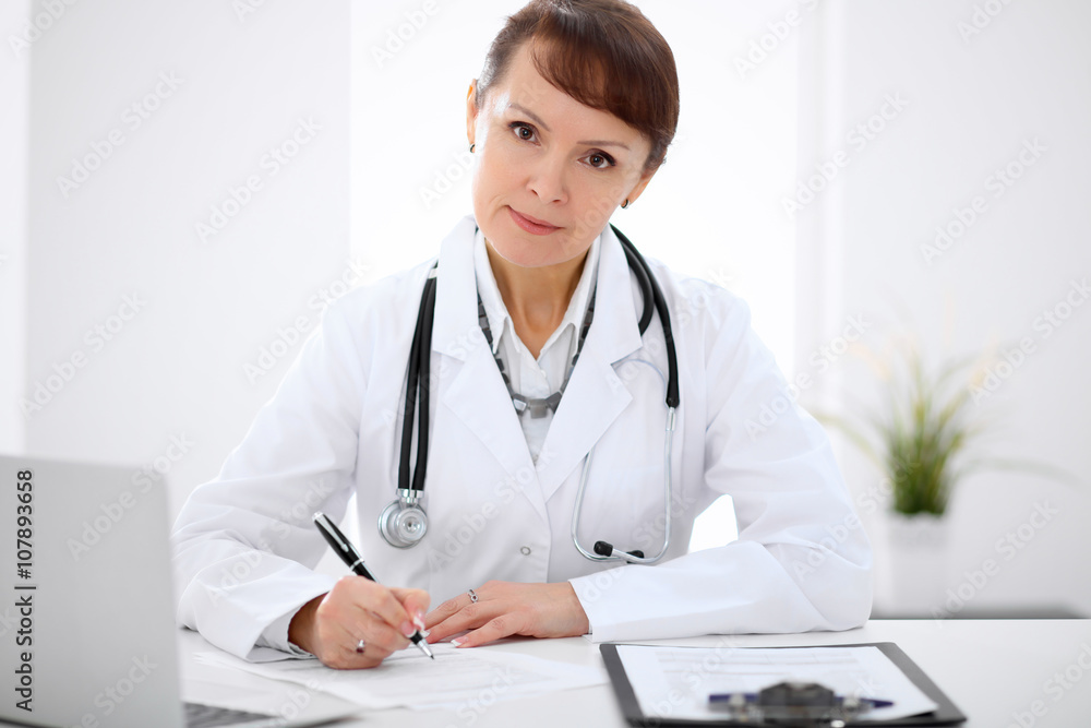 Woman doctor filling up medical history at the desk Woman doctor filling up medical history at the desk