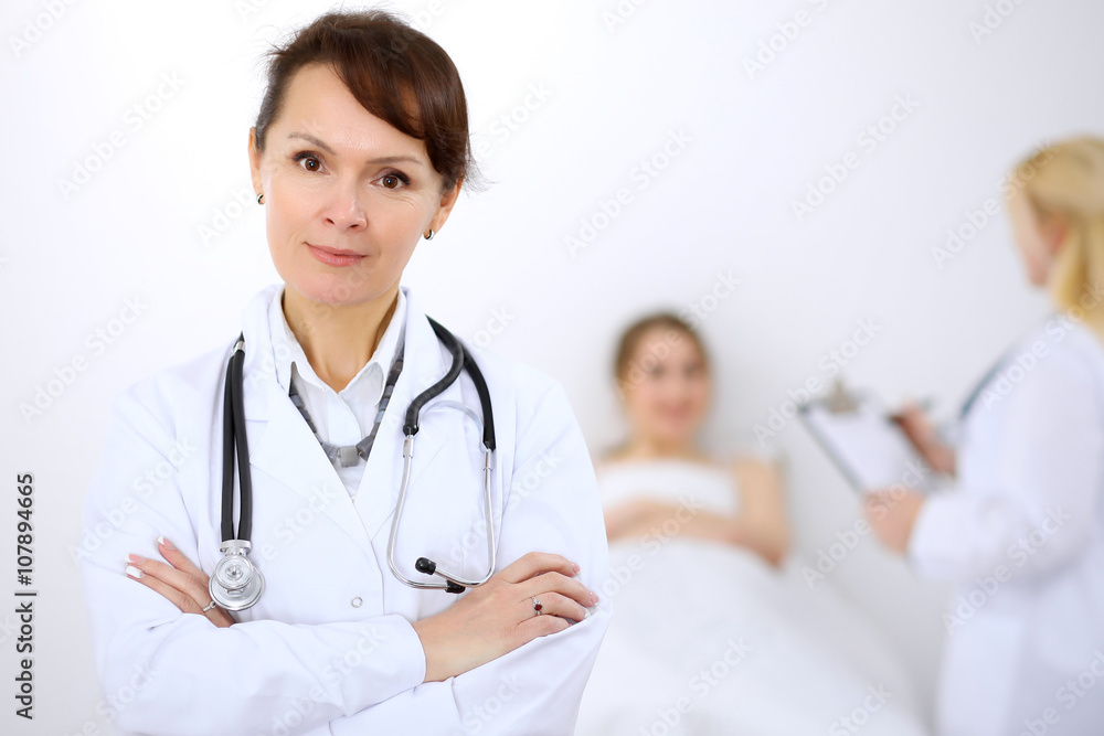 Female doctor smiling on the background with patient and his doctor Female doctor smiling on the background with patient and his doctor