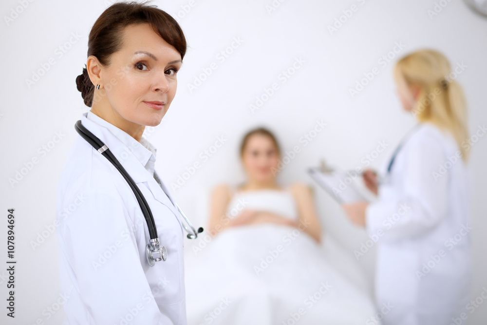 Female doctor smiling on the background with patient and his doctor Female doctor smiling on the background with patient and his doctor