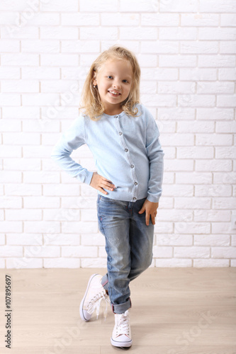 Little girl on a white brick wall background