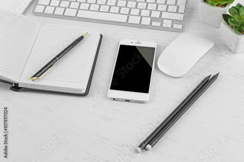 Obraz na płótnie Workplace with mobile phone, computer peripherals and stationery on light table