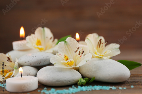 Spa still life with stones  flowers and candlelight on wooden background