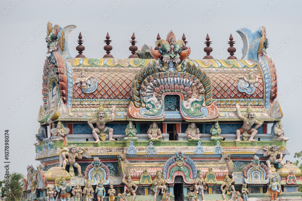 Trichy, India - October 15, 2013: Top of the gopuram, called Vimanam, shaped as a cake, with plenty of statues in pastel colors. Garudas on corners.