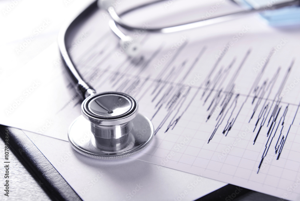 Cardiogram chart with medical stethoscope on table closeup Cardiogram chart with medical stethoscope on table closeup