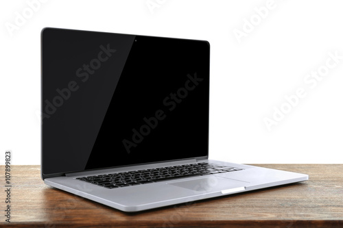 Laptop with black screen on wooden table against white background