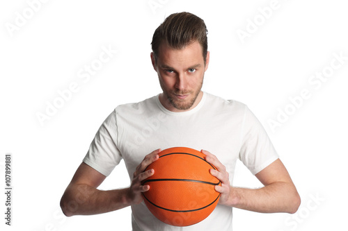 Focused basketball player wearing a white tshirt and holding a basketball. Standing against a white background staring at camera.