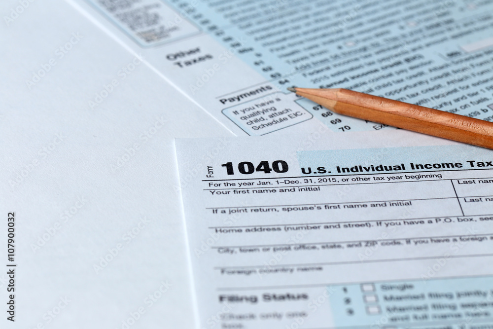 Obraz premium 1040 Individual Income Tax Return Form for 2015 year with a pencil to fill on the white desk, close up
