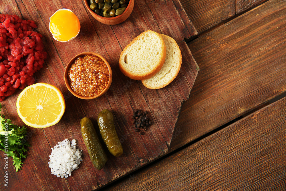 Beef tartare ingredients on wooden cutting board