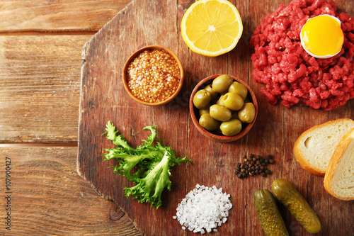 Beef tartare ingredients on wooden cutting board