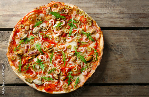 Pizza with seafood, red pepper and green olives on wooden table #107901010