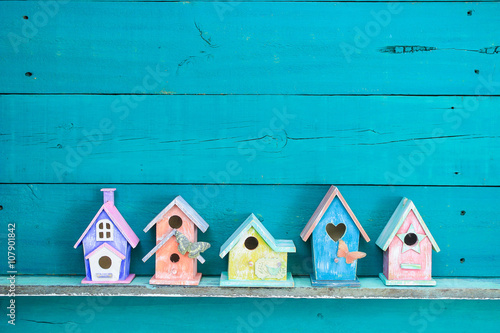 Fotografiet Row of colorful spring birdhouses with teal blue background