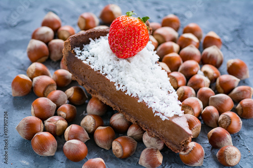 Slice of chocolate cake / chocolate pie decorated with coconut flakes and strawberry. Selective focus photo