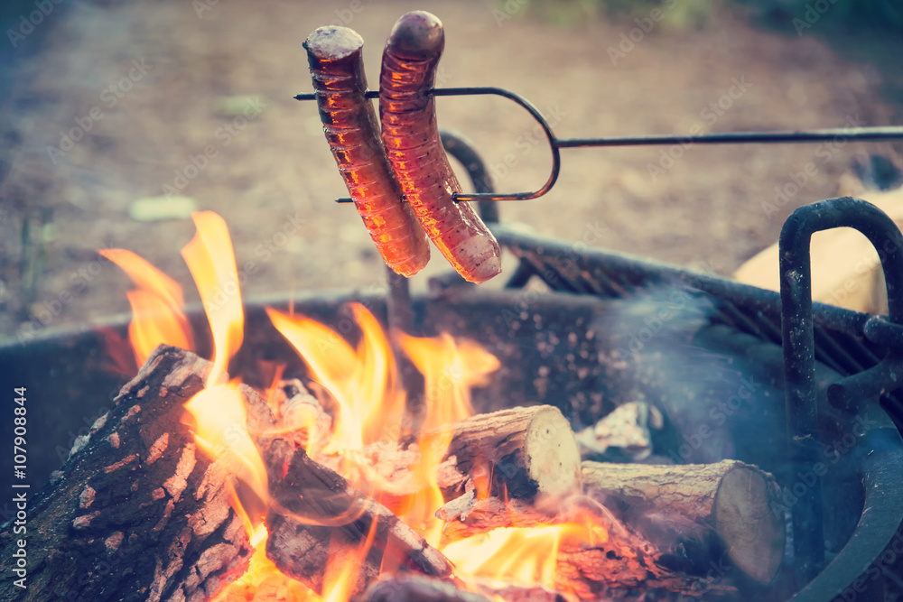 Preparing sausages on campfire, dinner on camping vacation  - obrazy, fototapety, plakaty 